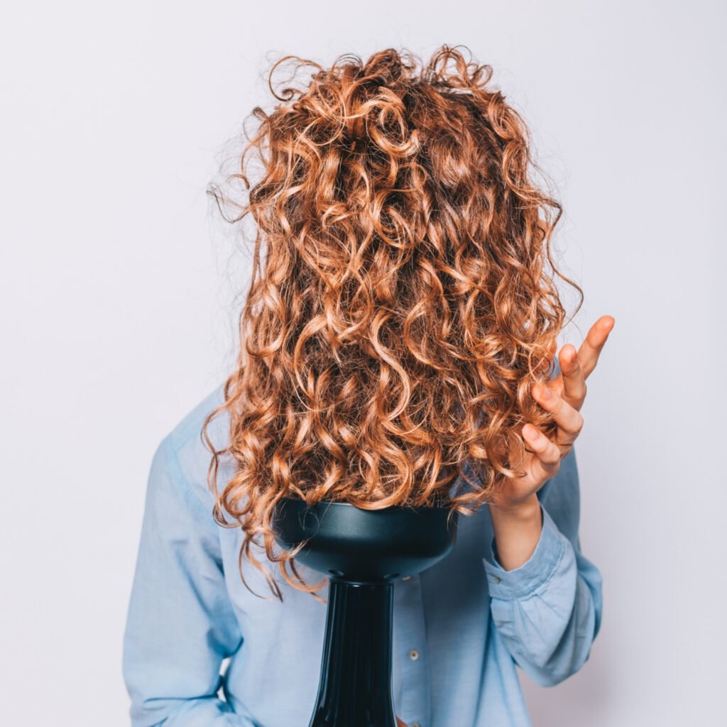 Frau trocknet die Haare mit einem Diffusor für einen perfekten Gelcast