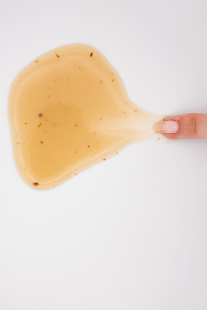 Finger, der durch Leinsamengel auf einem weißen Tisch, eine Spur zieht
